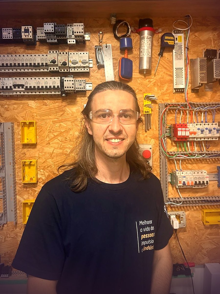 Prof. Homero de óculos de proteção, em frente à parede de quadros elétricos do estúdio